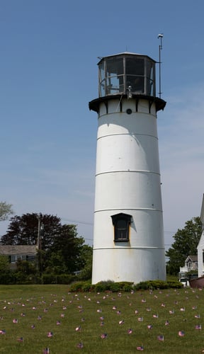 Chatham lighthouse on a sunny day with American flags and green lawn